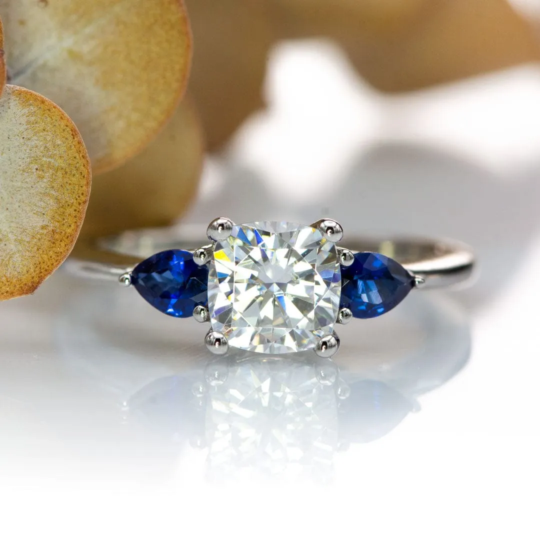 Tressa- Three Stone Engagement Ring, Prong set Cushion Moissanite & Pear Blue Sapphire Accents